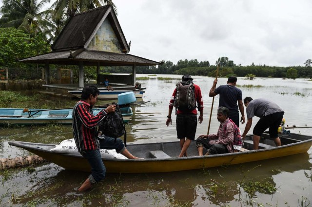 Local residents use a rental boat at the edge of floodwaters in Bendang Pak Yong, Malaysia's northeastern town of Tumpat, which borders with Thailand on January 6, 2017. Floods continued to inundate two northeast Malaysian states on January 5, as thousands of people remained in relief centres while others expressed fears of looting and sought aid. / AFP PHOTO / MOHD RASFAN