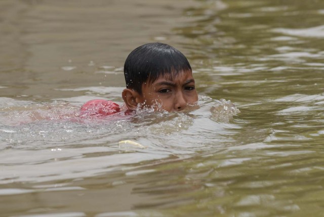 A child swims in floodwaters in Bendang Pak Yong, Malaysia's northeastern town of Tumpat, which borders with Thailand on January 6, 2017. Floods continued to inundate two northeast Malaysian states, as thousands of people remained in relief centres while others expressed fears of looting and sought aid. / AFP PHOTO / MOHD RASFAN