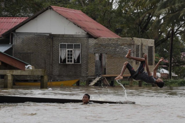 Boys play in floodwaters in Bendang Pak Yong, Malaysia's northeastern town of Tumpat, which borders with Thailand on January 6, 2017. Floods continued to inundate two northeast Malaysian states on January 5, as thousands of people remained in relief centres while others expressed fears of looting and sought aid. Floods continued to inundate two northeast Malaysian states, as thousands of people remained in relief centres while others expressed fears of looting and sought aid. / AFP PHOTO / MOHD RASFAN