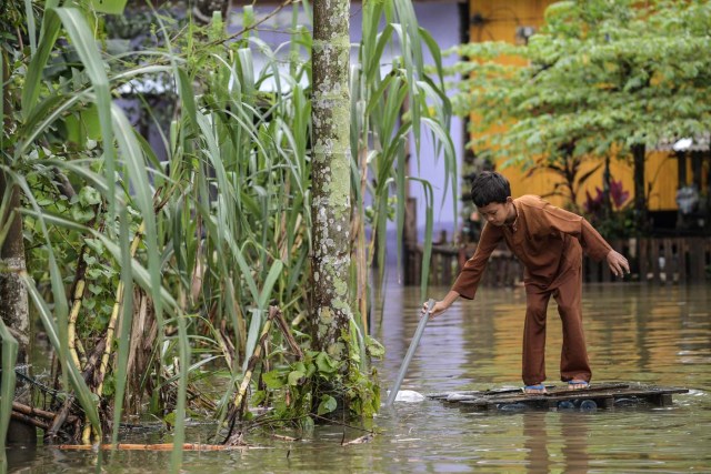 A boy travels through floodwaters in an improvised raft he made in Jal Besar, Malaysia's northeastern town of Tumpat, which borders with Thailand, on January 6, 2017. Serious flooding in Malaysia's northeast states for almost a week is showing some respite but has damaged homes, caused loss of income and disrupted schooling, victims said on January 6. / AFP PHOTO / Mohd RASFAN