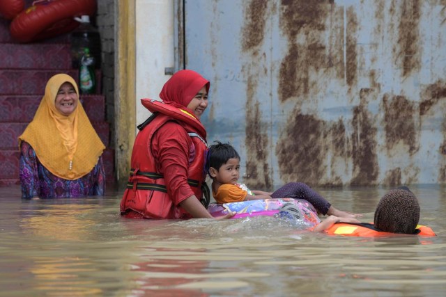 A family swims in floodwaters in Bendang Pak Yong, Malaysia's northeastern town of Tumpat, which borders with Thailand, on January 6, 2017. Serious flooding in Malaysia's northeast states for almost a week is showing some respite but has damaged homes, caused loss of income and disrupted schooling, victims said on January 6. / AFP PHOTO / Mohd RASFAN