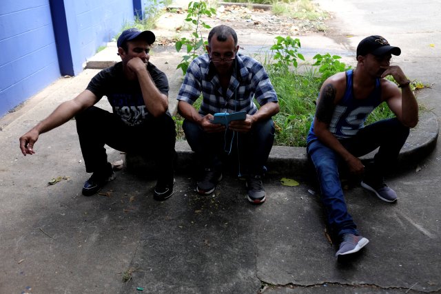 Inmigrantes cubanos escuchan las noticias en un teléfono móvil fuera de un albergue de Caritas en Ciudad de Panamá. 13 de enero de 2017. REUTERS/Melchor Herrera