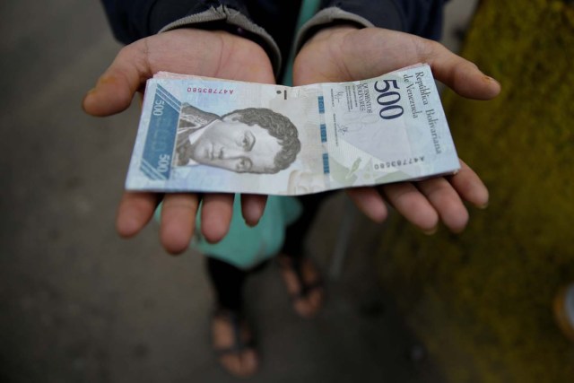 A woman holds 500 bolivar banknotes for a photo in Caracas, Venezuela January 16, 2017. REUTERS/Marco Bello