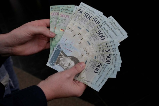 A man holds 500 and 5000 bolivar banknotes for a photo in Caracas, Venezuela January 16, 2017. REUTERS/Marco Bello