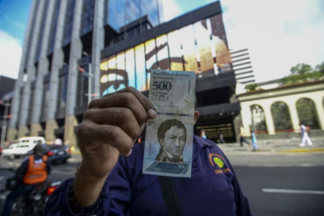 A man shows a new 500-Bolivar-note (74 cents of US dollar) in Caracas on January 16, 2017. A new family of currency will progressively come into circulation in the South American country that has the highest inflation rate in the world, which IMF forecasts say could soon hit 475 percent. / AFP PHOTO / JUAN BARRETO