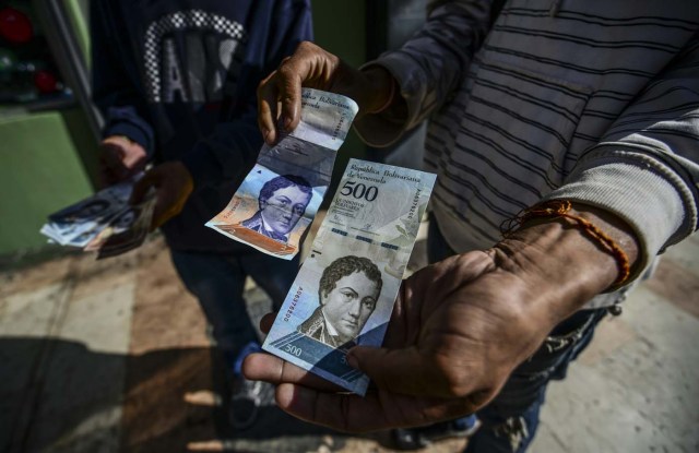 A man shows new 500-Bolivar-notes (74 cents of US dollar) in Caracas on January 16, 2017. A new family of currency will progressively come into circulation in the South American country that has the highest inflation rate in the world, which IMF forecasts say could soon hit 475 percent. / AFP PHOTO / JUAN BARRETO