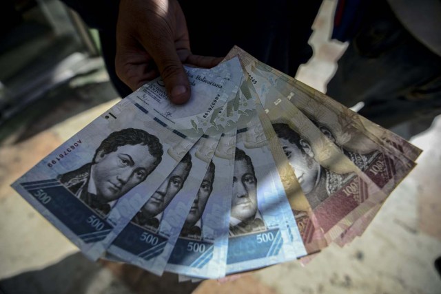 A man shows new 500-Bolivar-notes (74 cents of US dollar) in Caracas on January 16, 2017. A new family of currency will progressively come into circulation in the South American country that has the highest inflation rate in the world, which IMF forecasts say could soon hit 475 percent. / AFP PHOTO / JUAN BARRETO