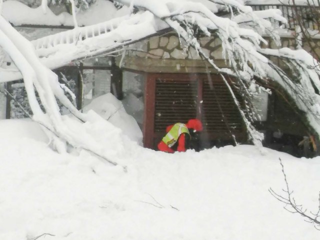 A member of Lazio's Alpine and Speleological Rescue Team is seen in front of the Hotel Rigopiano in Farindola, central Italy, hit by an avalanche, in this January 19, 2017 handout picture provided by Lazio's Alpine and Speleological Rescue Team. Soccorso Alpino Speleologico Lazio/Handout via REUTERS ATTENTION EDITORS - THIS IMAGE WAS PROVIDED BY A THIRD PARTY. EDITORIAL USE ONLY. NO RESALES. NO ARCHIVE.