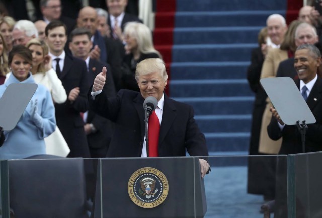 First lady Melania Trump (L) and outgoing U.S. President Barack Obama (R) looks on as U.S. President Donald Trump gives a thumbs up after being sworn in as the 45th president of the United States on the West front of the U.S. Capitol in Washington, U.S., January 20, 2017. REUTERS/Carlos Barria
