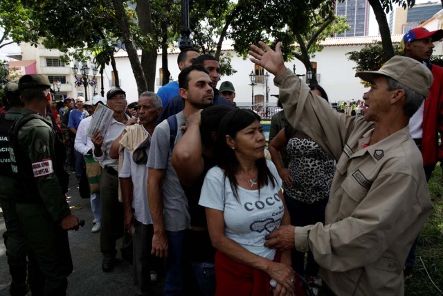 A militia member controls the crowd as people wait to apply for a card that will register them for government social programmes, in Caracas, Venezuela January 20, 2017. REUTERS/Marco Bello
