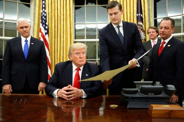 White House Staff Secretary Rob Porter (2nd R) gives U.S. President Donald Trump, flanked by Vice President Mike Pence (L) and Chief of Staff Reince Priebus (R) the document to confirming James Mattis his Secretary of Defense, his first signing in the Oval Office in Washington, U.S. January 20, 2017. REUTERS/Jonathan Ernst