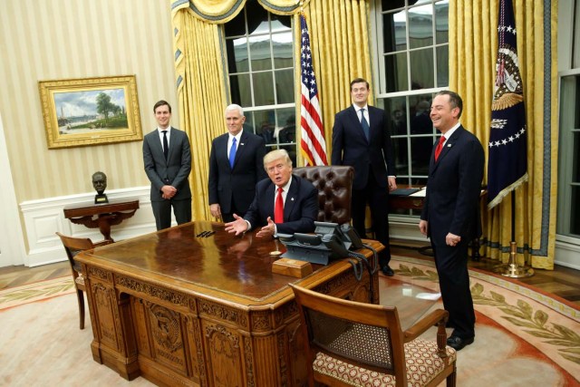 U.S. President Donald Trump, flanked by Senior Advisor Jared Kushner (standing, L-R), Vice President Mike Pence, Staff Secretary Rob Porter and Chief of Staff Reince Priebus, welcomes reporters into the Oval Office for him to sign his first executive orders at the White House in Washington, U.S. January 20, 2017. REUTERS/Jonathan Ernst