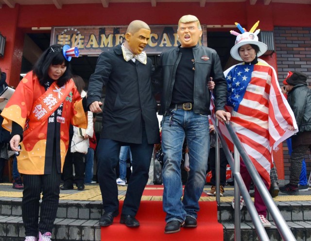 People wearing Barack Obama and Donald Trump masks walk down the stairs at JR Usa Station in the city of Usa in Oita Prefecture, southwestern Japan, in this photo taken by Kyodo on January 21, 2017. The train station changed its name to "Usa American Station" for the day to mark the inauguration of Donald Trump as U.S. president. Mandatory credit Kyodo/via REUTERS ATTENTION EDITORS - THIS IMAGE WAS PROVIDED BY A THIRD PARTY. EDITORIAL USE ONLY. MANDATORY CREDIT. JAPAN OUT. NO COMMERCIAL OR EDITORIAL SALES IN JAPAN. TPX IMAGES OF THE DAY