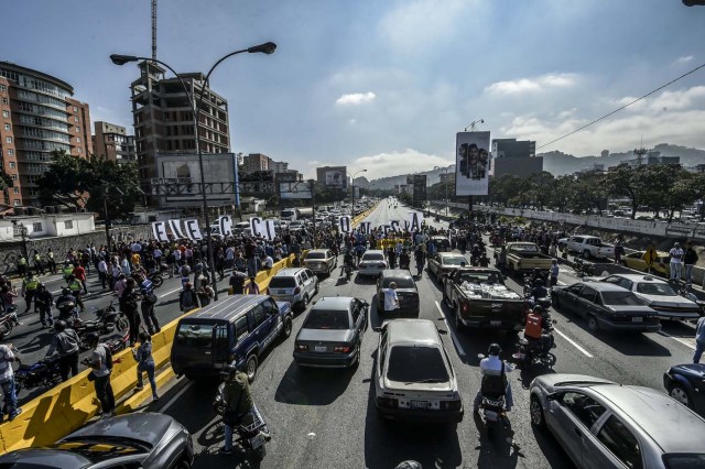 Opponents of Venezuelan President Nicolas Maduro protest at the main highway of Caracas on January 24, 2017. Venezuelan opponents protested to demand early elections, with the aim of ousting President Nicolas Maduro, who they blame for the profound political and economic crisis that has the country in its grip. / AFP PHOTO / JUAN BARRETO