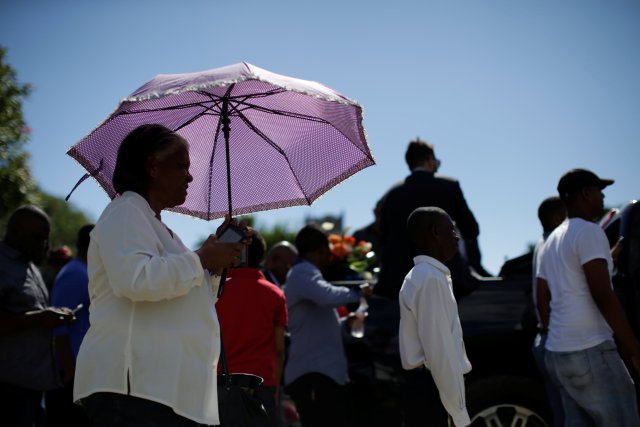 A mourner protects herself from the sun with an umbrella as she walks accompanying the coffin of Yordano Ventura, a Kansas City Royals baseball player who died in a car crash, during the funeral in Las Terrenas
