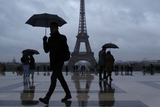 People protect themselves from the rain under umbrellas at Trocadero square near the Eiffel Tower in Paris, France, January 12, 2017. REUTERS/Gonzalo Fuentes