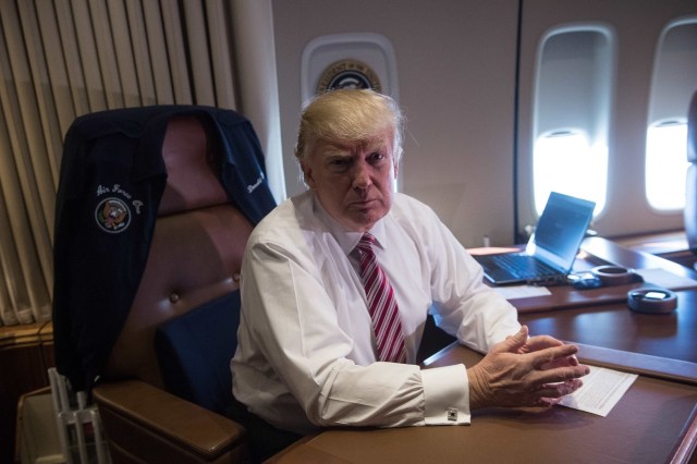 US President Donald Trump poses in his office aboard Air Force One at Andrews Air Force Base in Maryland after he returned from Philadelphia on January 26, 2017. / AFP PHOTO / NICHOLAS KAMM