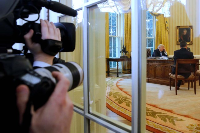 Photographers look on as U.S. President Donald Trump speaks by phone with Germany's Chancellor Angela Merkel in the Oval Office at the White House in Washington, U.S. January 28, 2017. REUTERS/Jonathan Ernst