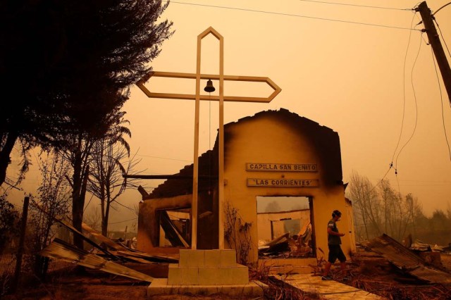 A man walks among the remains of a burnt church after a wildfire at the country's central-south regions in Santa Olga, Chile