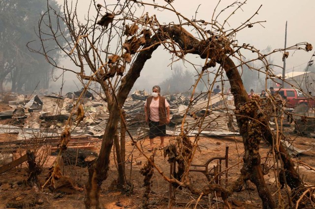 A woman walks amongst burnt houses in Santa Olga