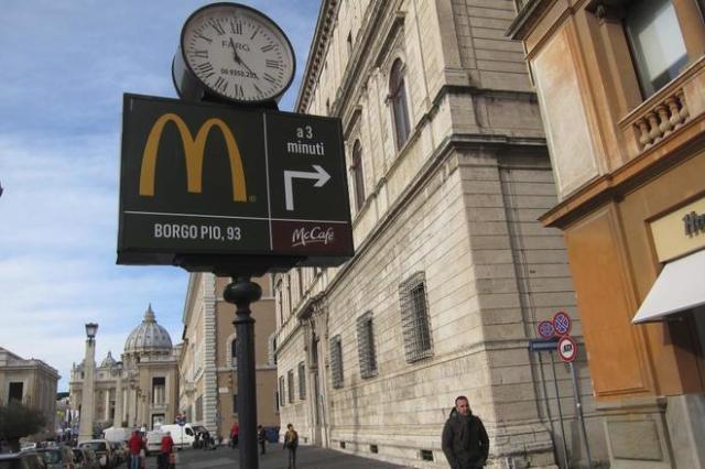 Cartel que indica el camino hacia el McDonald's del Vaticano, con la basílica de San Pedro al fondo. M. BERNABÉ