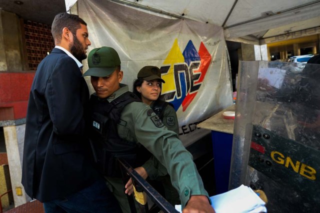 Venezuela's National Guard personnel prevent opposition deputy Juan Requesens from entering the National Electoral Council (CNE) in Caracas on February 2, 2017. A group of opposition lawmakers had their way blocked by police when they tried to get into the CNE to demand the organism to call for regional elections that were due to happen last year. / AFP PHOTO / FEDERICO PARRA