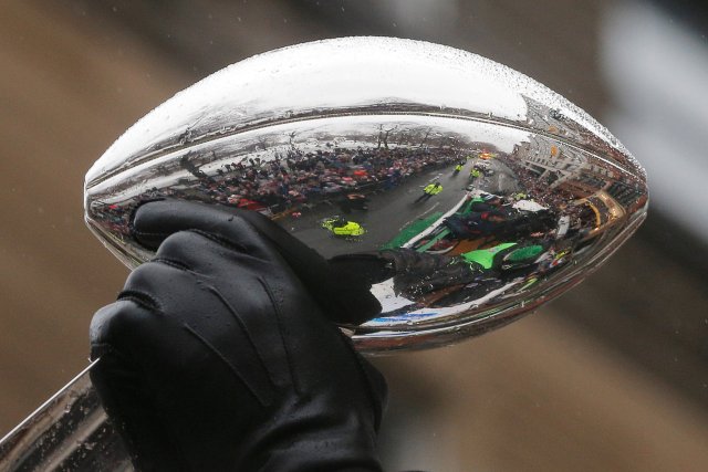 The crowds of fans lining the street are reflected in one of the team's five Vince Lombardi trophies carried by the New England Patriots players through the streets of Boston after winning Super Bowl LI, in Boston