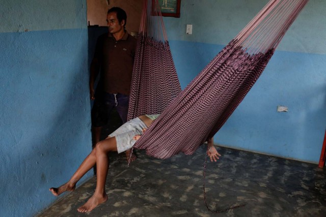 Tulio Medina, father of Eliannys Vivas, who died from diphtheria, stands next to his children as they rest in a hammock at their home in Pariaguan, Venezuela January 26, 2017. Picture taken January 26, 2017. REUTERS/Marco Bello