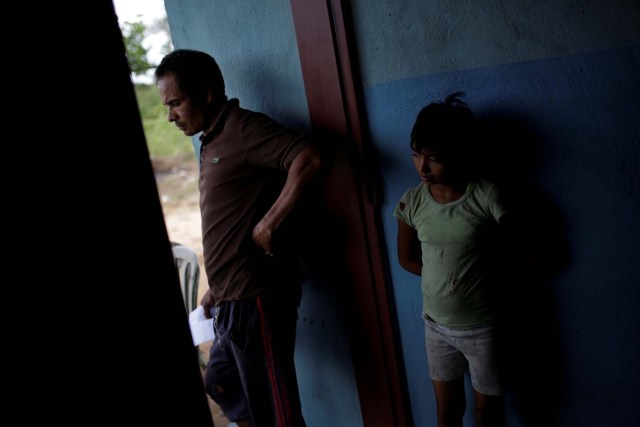 Tulio Medina (L), father of Eliannys Vivas, who died from diphtheria, stands next to one of his daughters at the entrance of their home in Pariaguan, Venezuela January 26, 2017. Picture taken January 26, 2017. REUTERS/Marco Bello