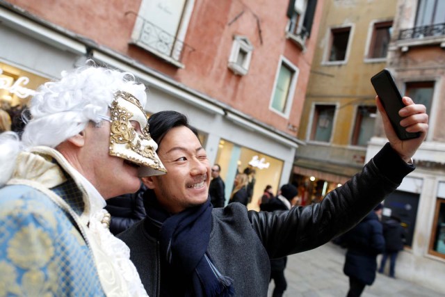 A tourist takes a selfie with a masked reveller during the Venice Carnival in Venice, Italy February 11, 2017. REUTERS/Tony Gentile