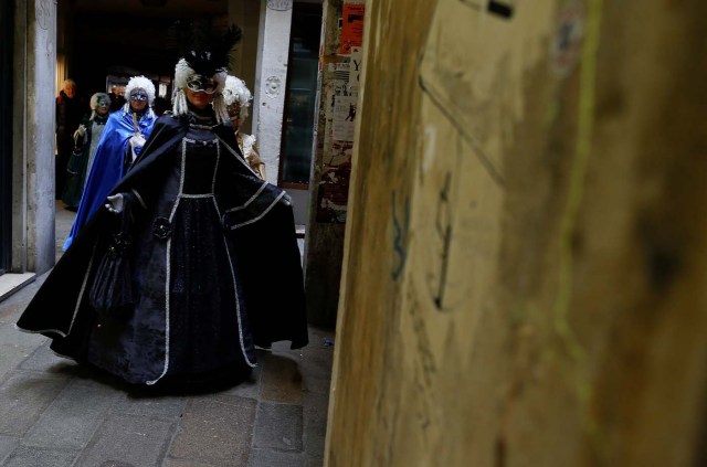 Masked revellers walk along a street during the Venice Carnival in Venice, Italy February 11, 2017. REUTERS/Tony Gentile