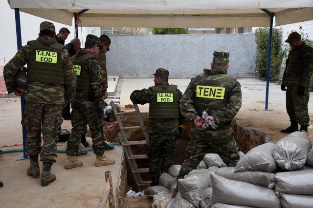 Military personnel of the Hellenic Army's Explosives Ordnance Disposal (EOD) stand over a hole in the ground where a 250 kg World War Two bomb that was found during excavation works at a gas station, before an operation to defuse it, in the northern city of Thessaloniki, Greece, February 12, 2017. REUTERS/Alexandros Avramidis