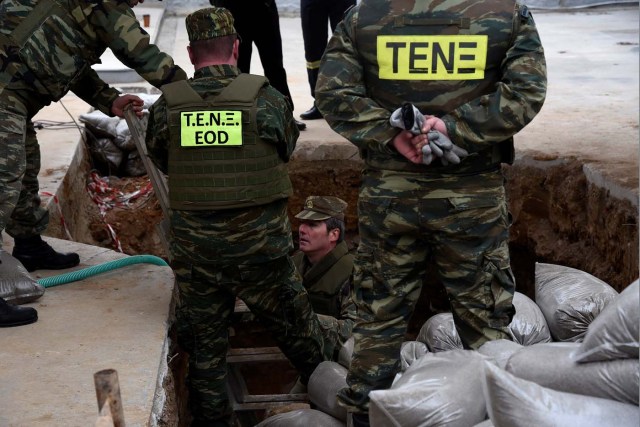 A military officer (C) of the Hellenic Army's Explosives Ordnance Disposal (EOD) is seen inside a hole in the ground where a 250 kg World War Two bomb was found during excavation works at a gas station, before an operation to defuse it, in the northern city of Thessaloniki, Greece, February 12, 2017. REUTERS/Alexandros Avramidis
