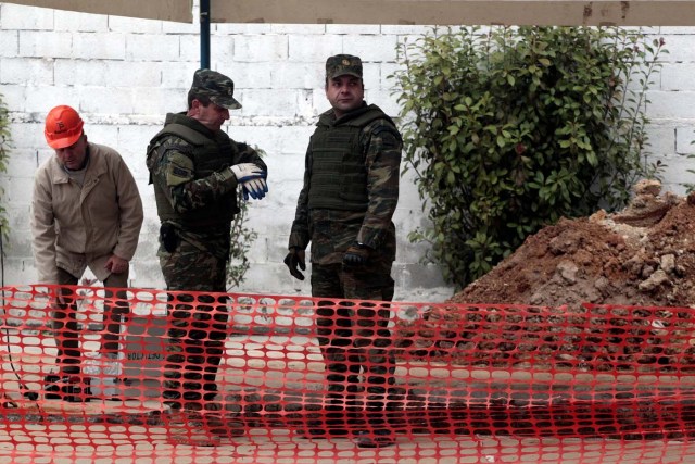 Military officers of the Hellenic Army's Explosives Ordnance Disposal (EOD) stand over a hole in the ground where a 250 kg World War Two bomb was found during excavation works at a gas station, before an operation to defuse it, in the northern city of Thessaloniki, Greece, February 12, 2017. REUTERS/Alexandros Avramidis