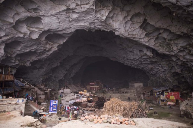 This photo taken on November 6, 2016 shows a general view of Zhongdong village, where a group of 18 families live inside an enormous natural cave. The final hold-outs of the country's "last cave-dwelling" village have had modern conveniences, like electricity, for years. But their only access to the outside world is a footpath winding through Guizhou province's rugged mountain terrain. / AFP PHOTO / FRED DUFOUR / TO GO WITH China-economy-tourism,FEATURE by Becky Davis