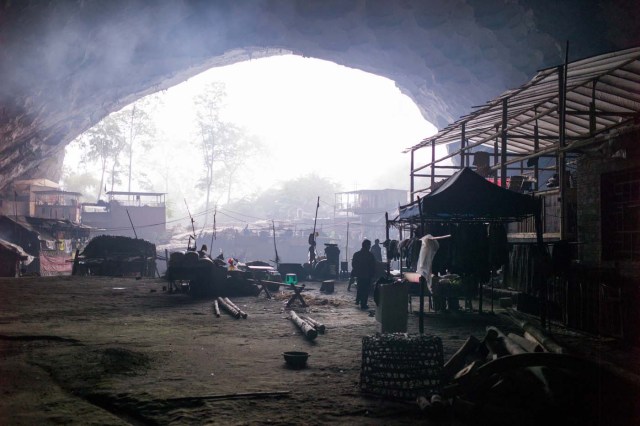 This photo taken on November 6, 2016 shows a general view of the village of Zhongdong, where a group of 18 families live inside an enormous natural cave. The final hold-outs of the country's "last cave-dwelling" village have had modern conveniences, like electricity, for years. But their only access to the outside world is a footpath winding through Guizhou province's rugged mountain terrain. / AFP PHOTO / FRED DUFOUR / TO GO WITH China-economy-tourism,FEATURE by Becky Davis