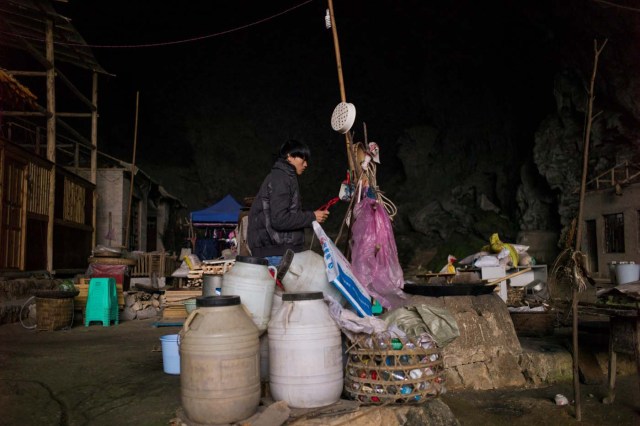 This photo taken on November 6, 2016 shows a man standing among his belongings in Zhongdong village, where a group of 18 families live inside an enormous natural cave. The final hold-outs of the country's "last cave-dwelling" village have had modern conveniences, like electricity, for years. But their only access to the outside world is a footpath winding through Guizhou province's rugged mountain terrain. / AFP PHOTO / FRED DUFOUR / TO GO WITH China-economy-tourism,FEATURE by Becky Davis