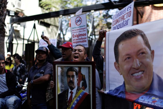 Supporters of Venezuela's President Nicolas Maduro hold images of him and Venezuela's late President Hugo Chavez and shout slogans during a gathering to support Maduro’s government order of suspension of CNN's Spanish-language service outside the National Commission of Telecommunications (CONATEL), in Caracas, Venezuela February 16, 2017. REUTERS/Marco Bello