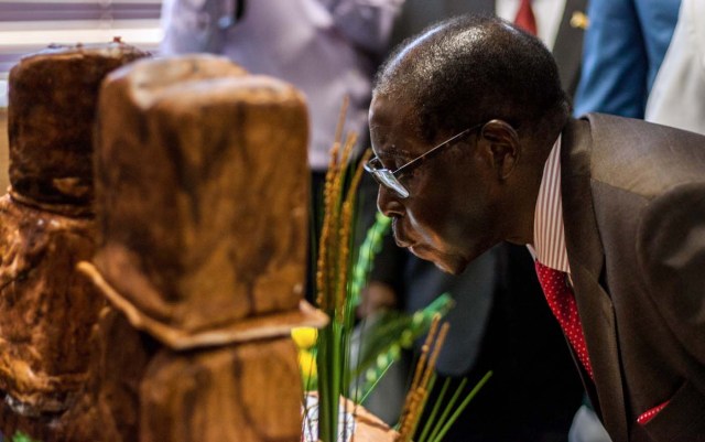 Zimbabwe's President Robert Mugabe blows out candles during a private ceremony to celebrate his 93rd birthday on February 21, 2017 in Harare.  Mugabe, the world's oldest national ruler, turned 93, using a long and occasionally rambling interview to vow to remain in power despite growing signs of frailty. / AFP PHOTO / Jekesai NJIKIZANA