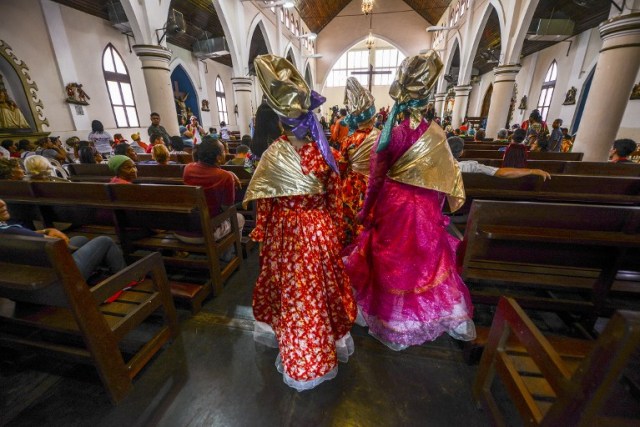 Women dressed as "madamas" attend a mass before the beginning of the Carnival in El Callao, Bolivar state, Venezuela on February 26, 2017. El Callao's carnival was recently named Unesco's Intangible Cultural Heritage of Humanity and is led by the madamas, the pillars of Callaoense identity representing Antillean matrons considered the communicators of values, who dance and wear colourful dresses. / AFP PHOTO / JUAN BARRETO