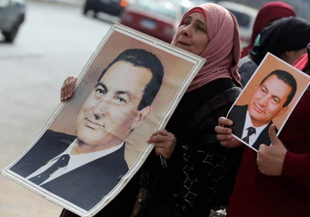 Supporters of former Egyptian President Hosni Mubarak hold up his pictures as they wait for him to be transferred to a court, in front of Maadi military hospital in Cairo, Egypt, March 2, 2017. REUTERS/Mohamed Abd El Ghany