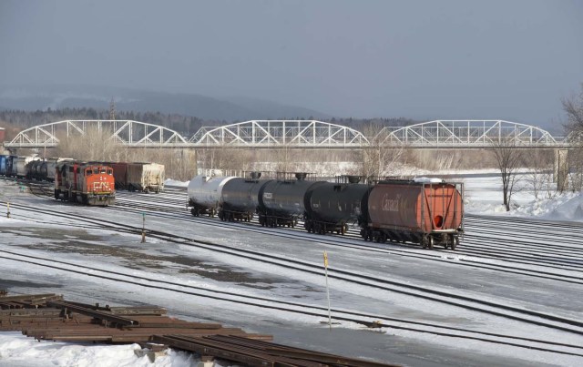 Railroad cars are parked in the foreground with the international bridge, crossing of the St. John River, in the background March 2, 2017, in the border town of Edmundston, New Brunswick. Edmundston is on the left and Madawaska, Maine is on the right end of the bridge. / AFP PHOTO / DON EMMERT