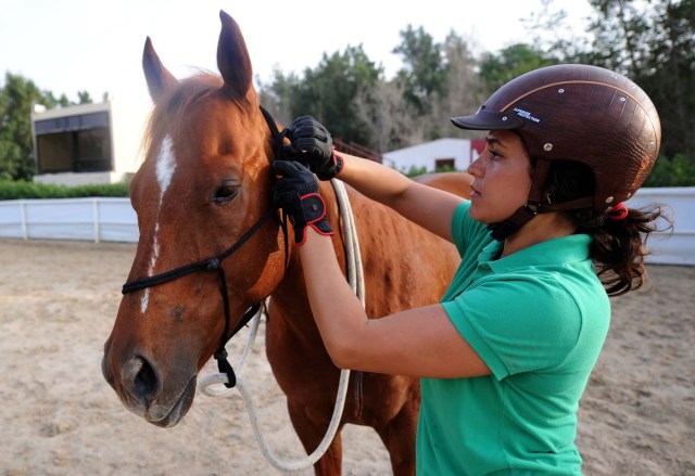 Saudi Dana al-Gosaibi trains a horse on March 1, 2017, in the Red Sea city of Jeddah. The 35-year-old Saudi horse trainer dreams of opening her own stables to focus on "a more gentle" way of training horses than the standard approach in the male-dominated kingdom. / AFP PHOTO / Amer HILABI