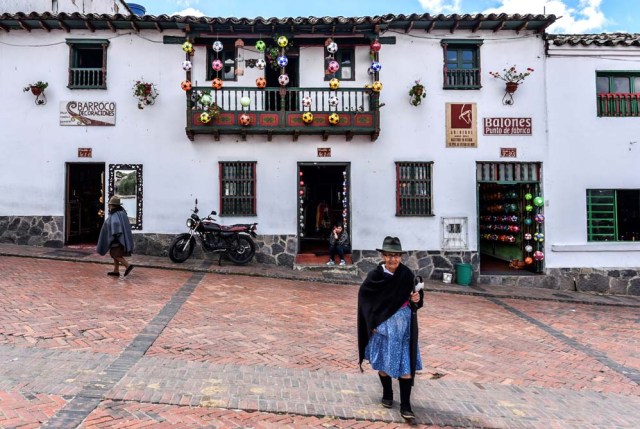 An elderly woman walks in front of ball factory in Mongui, in the Colombian department of Boyaca, on February 13, 2017. Mongui, in the central mountains of Colombia, has about 20 football factories that make balls mainly for football and micro-football. About a quarter of the town's 4,900 inhabitants work in these factories. / AFP PHOTO / Luis ACOSTA