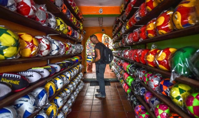 A tourist visits a ball factory in Mongui, in the Colombian department of Boyaca, on February 13, 2017. Mongui, in the central mountains of Colombia, has about 20 football factories that make balls mainly for football and micro-football. About a quarter of the town's 4,900 inhabitants work in these factories. / AFP PHOTO / Luis ACOSTA