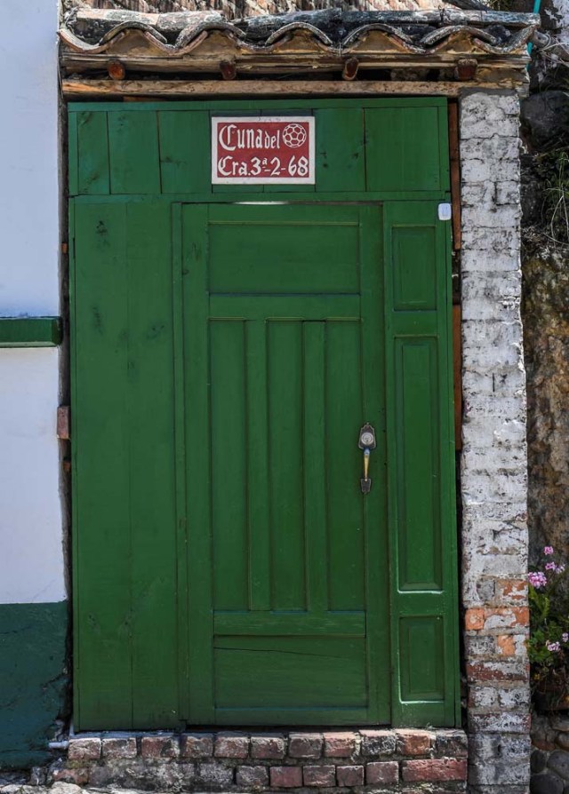 Picture of a door with a sign reading "Cradle of the Football" in Mongui, in the Colombian department of Boyaca, on February 13, 2017. Mongui, in the central mountains of Colombia, has about 20 ball factories that make balls mainly for football and micro-football. About a quarter of the town's 4,900 inhabitants work in these factories. / AFP PHOTO / Luis ACOSTA