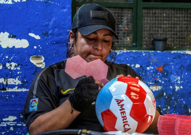 A worker makes footballs at a ball factory in Mongui, in the Colombian department of Boyaca, on February 13, 2017. Mongui, in the central mountains of Colombia, has about 20 ball factories that make balls mainly for football and micro-football. About a quarter of the town's 4,900 inhabitants work in these factories. / AFP PHOTO / Luis ACOSTA
