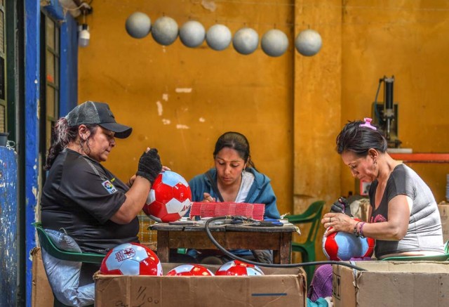 Workers make footballs at a ball factory in Mongui, in the Colombian department of Boyaca, on February 13, 2017. Mongui, in the central mountains of Colombia, has about 20 ball factories that make balls mainly for football and micro-football. About a quarter of the town's 4,900 inhabitants work in these factories. / AFP PHOTO / Luis ACOSTA