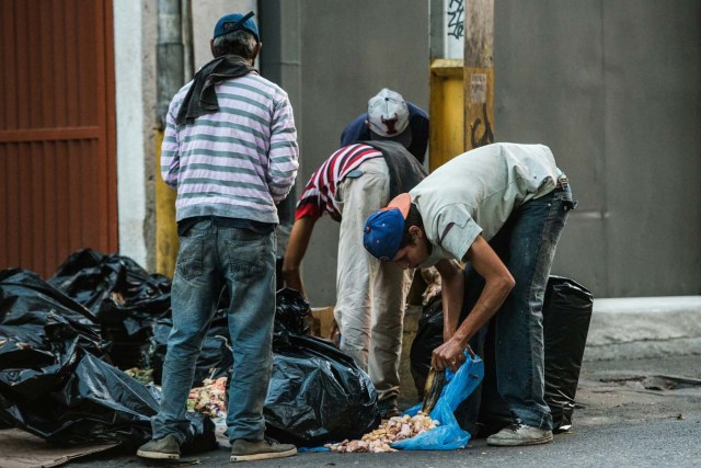 People scavange for food in the streets of Caracas on February 22, 2017. Venezuelan President Nicolas Maduro is resisting opposition efforts to hold a vote on removing him from office. The opposition blames him for an economic crisis that has caused food shortages. / AFP PHOTO / Federico PARRA