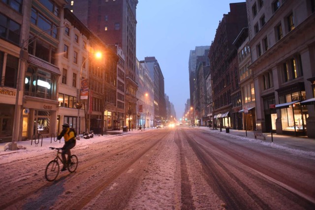 A cyclist bikes through an empty street in Midtown Manhattan during a snowstorm in New York on March 14, 2017. Winter Storm Stella dumped snow and sleet Tuesday across the northeastern United States where thousands of flights were canceled and schools closed, but appeared less severe than initially forecast. After daybreak the National Weather Service (NWS) revised down its predicted snow accumulation for the city of New York, saying that the storm had moved across the coast. / AFP PHOTO / ERIC BARADAT